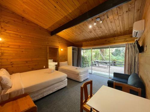 罗托鲁瓦Lakes Lodge Okataina的酒店客房带两张床和一张桌子以及椅子。
