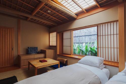 京都元奈古旅馆的一间卧室配有一张床、一张桌子和一个窗户。