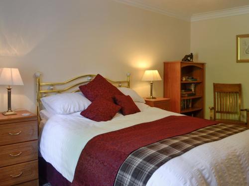 StraitonBelstane Cottage的一间卧室配有一张带红色枕头的大床