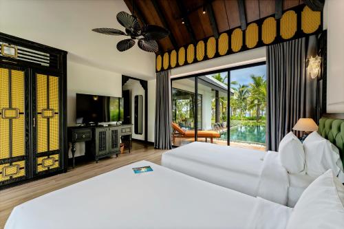 会安Bliss Hoi An Beach Resort & Wellness的卧室配有一张白色大床和电视。