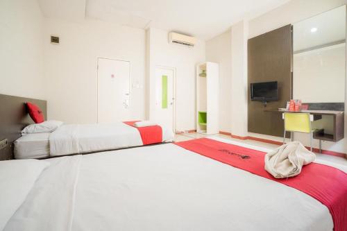 纳闽巴霍RedDoorz near Pantai Pede的一间卧室配有两张床和电视。