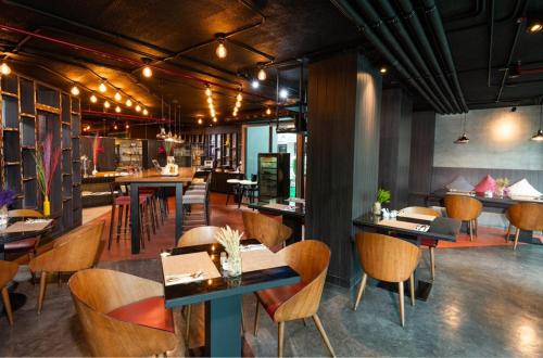 曼谷Maitria Mode Sukhumvit 15 Bangkok - A Chatrium Collection的一间带桌椅的餐厅和一间酒吧