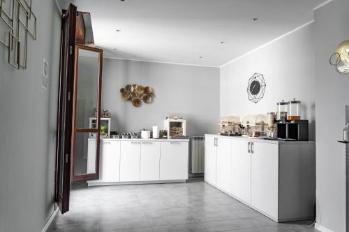 米兰Carlo Goldoni Hotel的厨房配有白色橱柜和瓷砖地板。