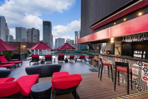 曼谷Maitria Mode Sukhumvit 15 Bangkok - A Chatrium Collection的屋顶酒吧,大楼内摆放着红色的椅子和桌子