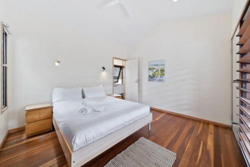 波因特卢考特Laguna的一间卧室配有一张带白色床单和镜子的床