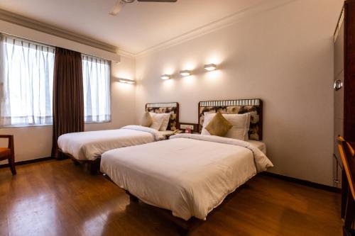 艾哈迈达巴德3 BY OYO Nami Residency Ahmedabad的配有白色床单的酒店客房内的两张床