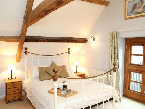 斯通豪斯Stanley Barn的卧室设有白色的床和木梁。
