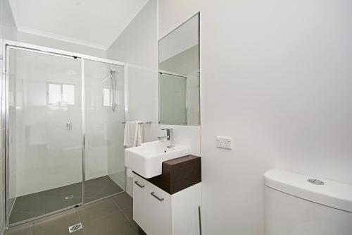 Cooroy库罗伊豪华汽车旅馆公寓的白色的浴室设有水槽和淋浴。