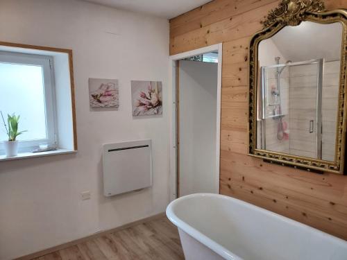 热拉梅Chez Laetitia的浴室配有白色浴缸和镜子