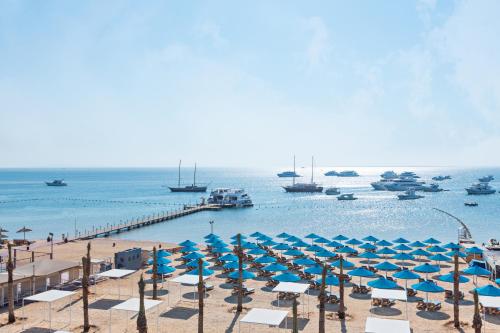 赫尔格达Pickalbatros Blu Spa Resort - Adults Friendly 16 Years Plus- Ultra All-Inclusive的海滩上设有蓝色的遮阳伞和船只