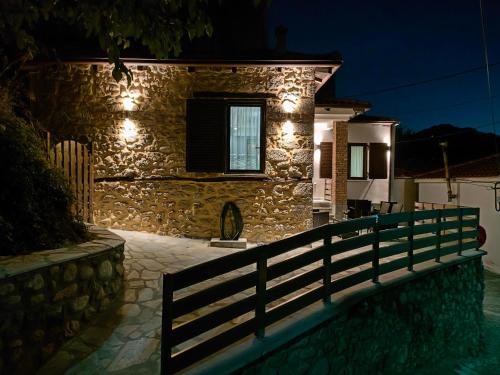 卡兰巴卡Dream Nest Meteora的一座石头房子,晚上在前面有栅栏