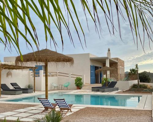 卡塔赫纳Villa privada en entorno rural的别墅 - 带带椅子和遮阳伞的游泳池