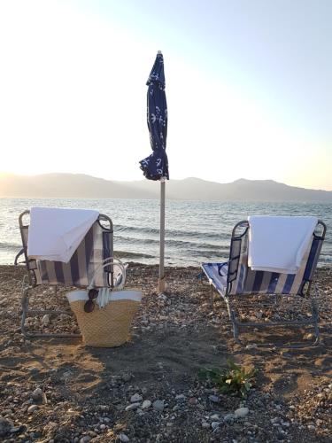 LisvórionBeach house in Skala Polichnitou, Lesvos, Greece的海滩上的两把椅子和一把遮阳伞