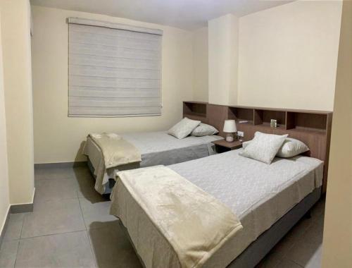 瓜亚基尔Garzota Suites Gardens的配有窗户的酒店客房内的两张床