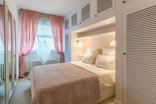比亚里茨Appartement de 50 m2 à quelques mètres des commerces et des plages的一间卧室配有床和一个带粉红色窗帘的窗户。