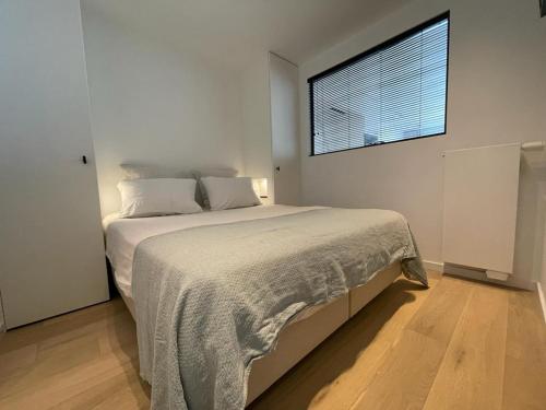 克诺克－海斯特Royal Knokke的白色卧室设有一张大床和窗户