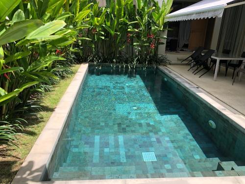 普吉镇Superbe villa tropicale avec piscine privée Phuket的庭院内一个蓝色瓷砖的游泳池