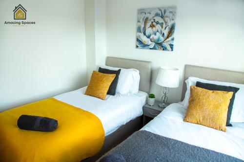 沃灵顿Cosy 2 Bed Flat Sleeps 4 with Free Parking by Amazing Spaces Relocations Ltd的一间卧室配有两张带黄色枕头的床