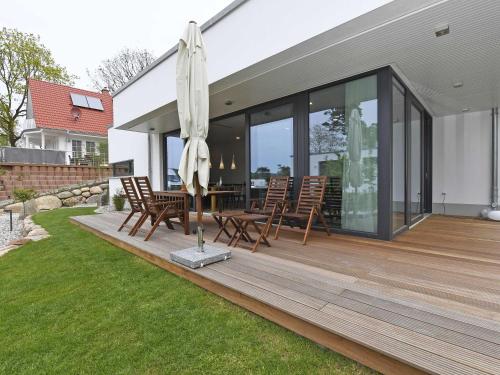 奥斯赛拜-塞林Haus Wetterhexe - FeWo 01的木甲板配有桌子和遮阳伞