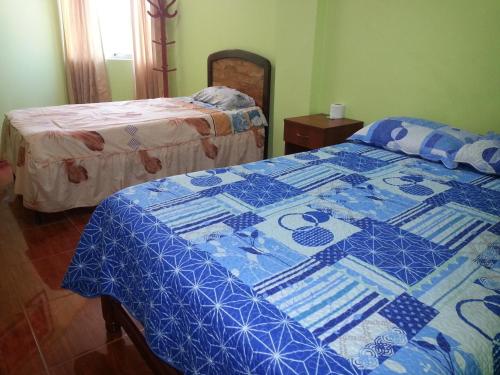 伊洛Hostal Puerto Ingles的一间卧室配有两张带蓝白色棉被的床