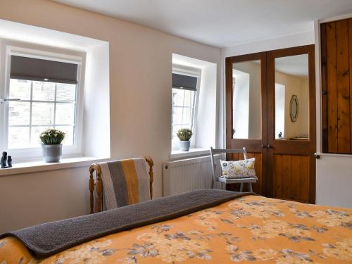 SilsdenBeckside Cottage的一间卧室设有一张床和两个窗户。