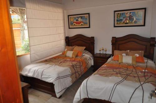 伊瓦拉Lujosa Quinta Vacacional Ibarra的一间卧室设有两张床和窗户。