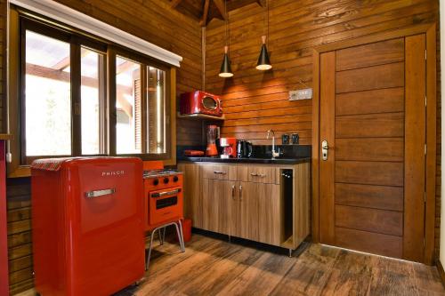 格拉玛多Stillo Gramado Dutra的小木屋内的厨房配有红色冰箱