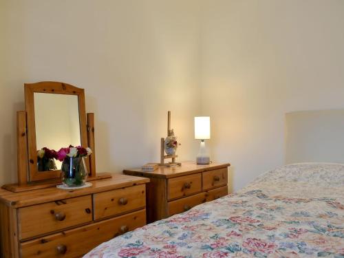 阿伯劳尔Spey Cottage的一间卧室配有一张床和一个带镜子的梳妆台