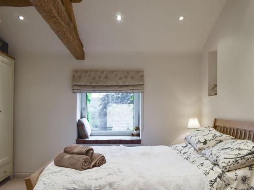 班福德Easter Cottage的一间卧室配有一张床和一个带椅子的窗户