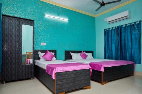 加尔各答deb Guest House And Banquet hall的配有两张蓝色墙壁和粉红色床单的客房内的床铺