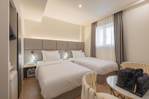 庆州Denbasta Hotel Heritage的酒店客房设有两张床和一张桌子。