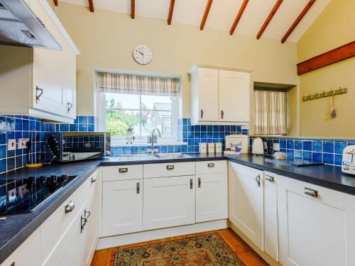 CaeathroBeudy - Uk31388的厨房配有白色橱柜和蓝色瓷砖墙。