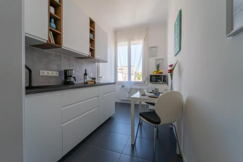 布达佩斯Sunhill Studio的厨房配有白色橱柜、桌子和椅子
