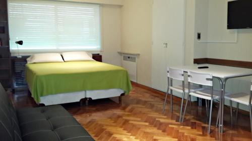 布宜诺斯艾利斯Studio Maipu的一间卧室配有一张床、一张桌子和一台电视