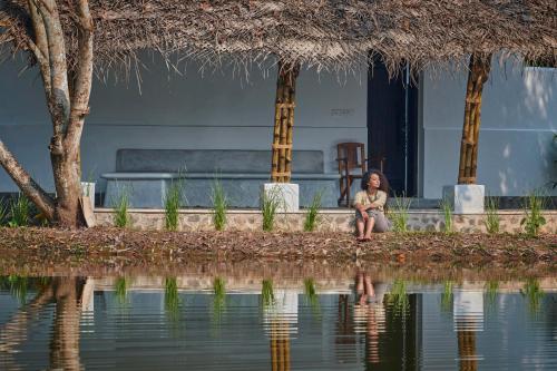 马拉利库兰Xandari Pearl Beach Resort的坐在水体旁的女人