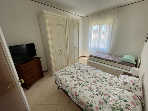 玛丽安迪安多拉Appartamento Note d’estate的一间卧室配有一张床、一个橱柜和一台电视