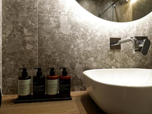 AchílleionKaiser Luxury Suites的浴室位于水槽旁的架子上,配有3瓶洗发水。