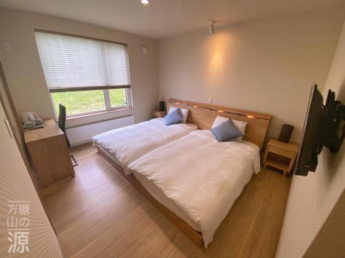富良野山の源-Yama No Minamoto的一间卧室配有一张带白色床单的床和一扇窗户。