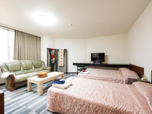 SagamichōTabist Ooriya Kochi的酒店客房,设有两张床和一张沙发