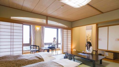 雫石町Hotel Morinokaze Oshuku的女人坐在卧室的桌子上