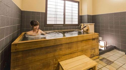 雫石町Hotel Morinokaze Oshuku的女性使用大型木制浴缸