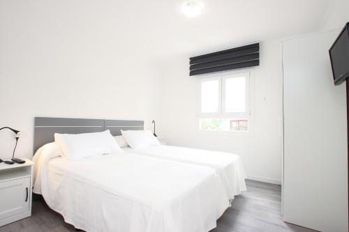 波连萨港Apt RIERES的白色的卧室设有白色的床和窗户。