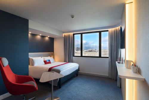 鲁瓦西昂法兰西巴黎CDG机场智选假日酒店的酒店客房,配有一张床和一张红色椅子