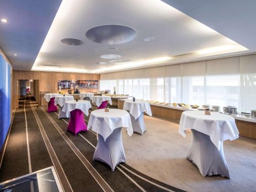 布鲁塞尔布鲁塞尔中心铂尔曼酒店 的一间设有白色桌子和紫色椅子的用餐室