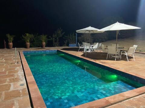 里贝朗克拉鲁Pousada Villa Paraizo的一个带桌椅和遮阳伞的游泳池