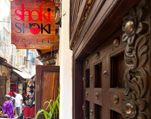 桑给巴尔Shoki Shoki Hostel的商店的门,上面有标志