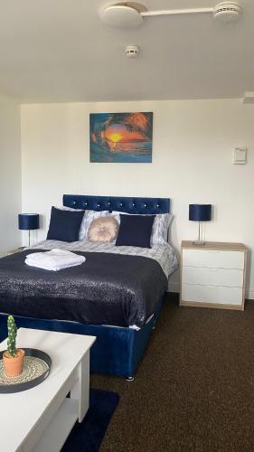 哈德斯菲尔德Bv Cosy Studio Eleven At Deighton Huddersfield的一间卧室配有蓝色的床和两张桌子
