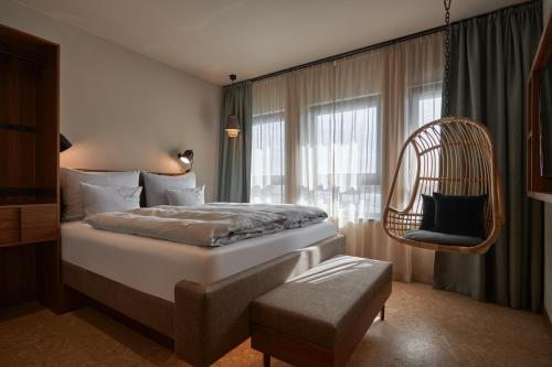 萨尔茨堡Cocoon Salzburg的卧室配有床、椅子和窗户。