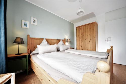 万根沃格Haus Blümlein Wangerooge的卧室配有一张白色大床和木制床头板