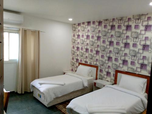 楠普拉RESIDENCIAL AFRICA,LDA-NAMPULA的一间设有两张床的客房和一面紫色方形的墙壁